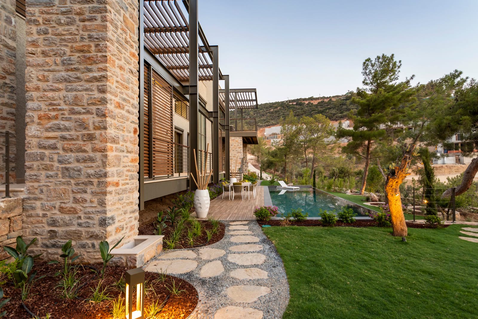 Modern stone-clad villa facade with pool and landscaped courtyard